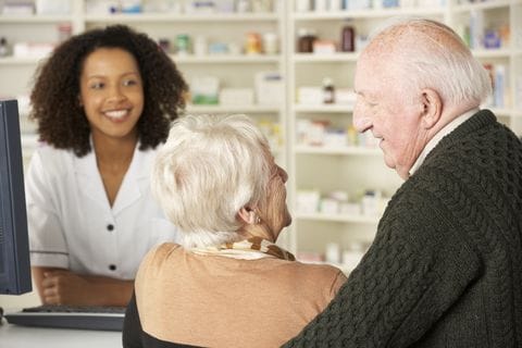 Pharmacist assisting an older couple at the pharmacy counter
